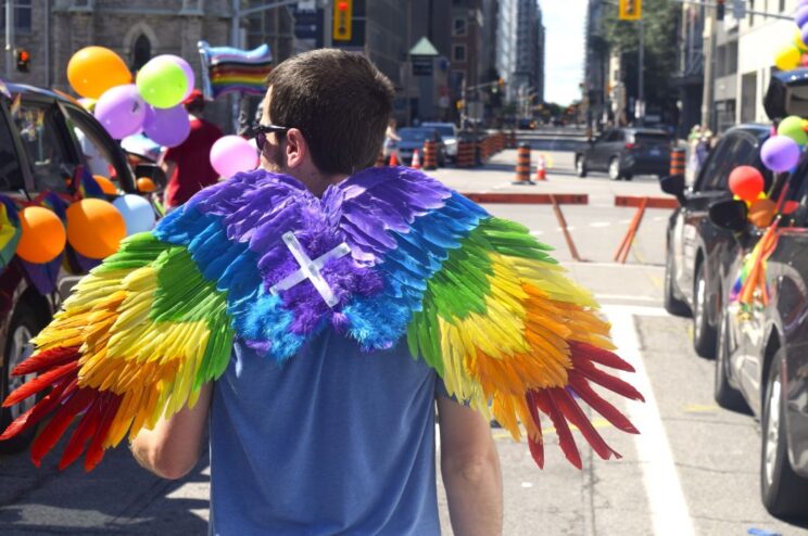 Person wearing large rainbow wings